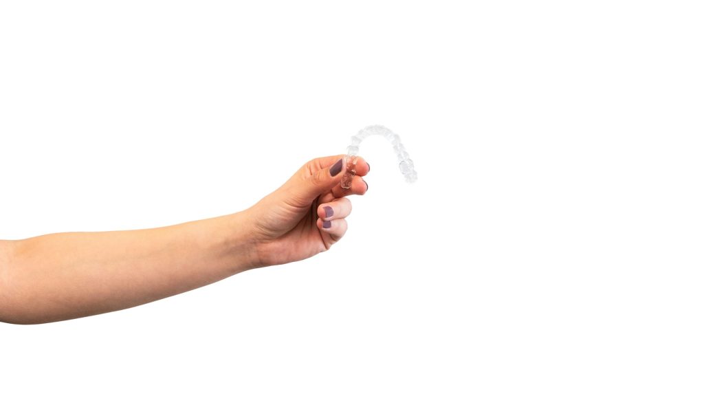 Adult woman holds invisalign transparent braces for dental correction.